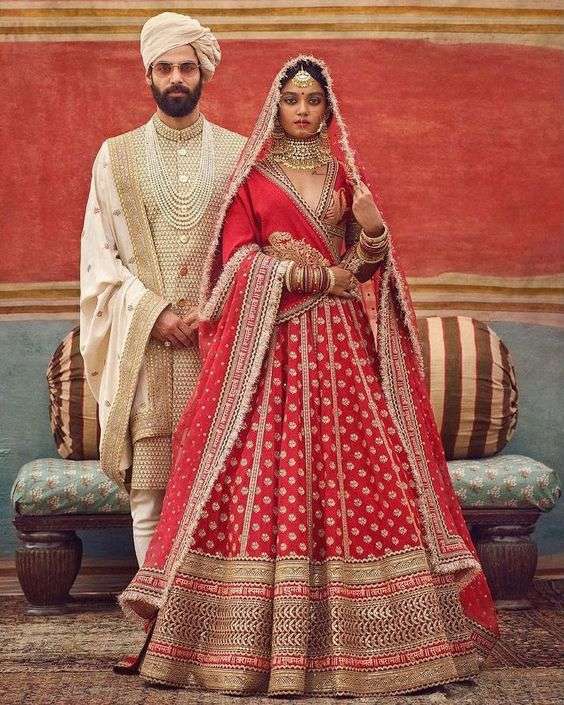 image of red lehenga with gold zardozi work and golden sherwani with red dupatta and pagdi